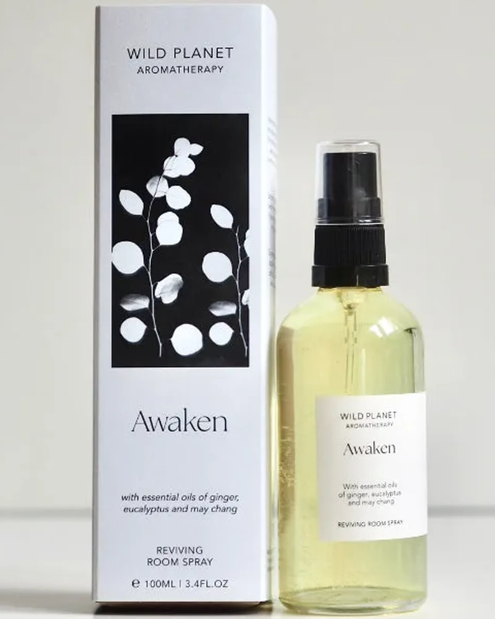 A clear glass bottle of Awaken room spray with a black spray pump and a small cream label naming the scent.