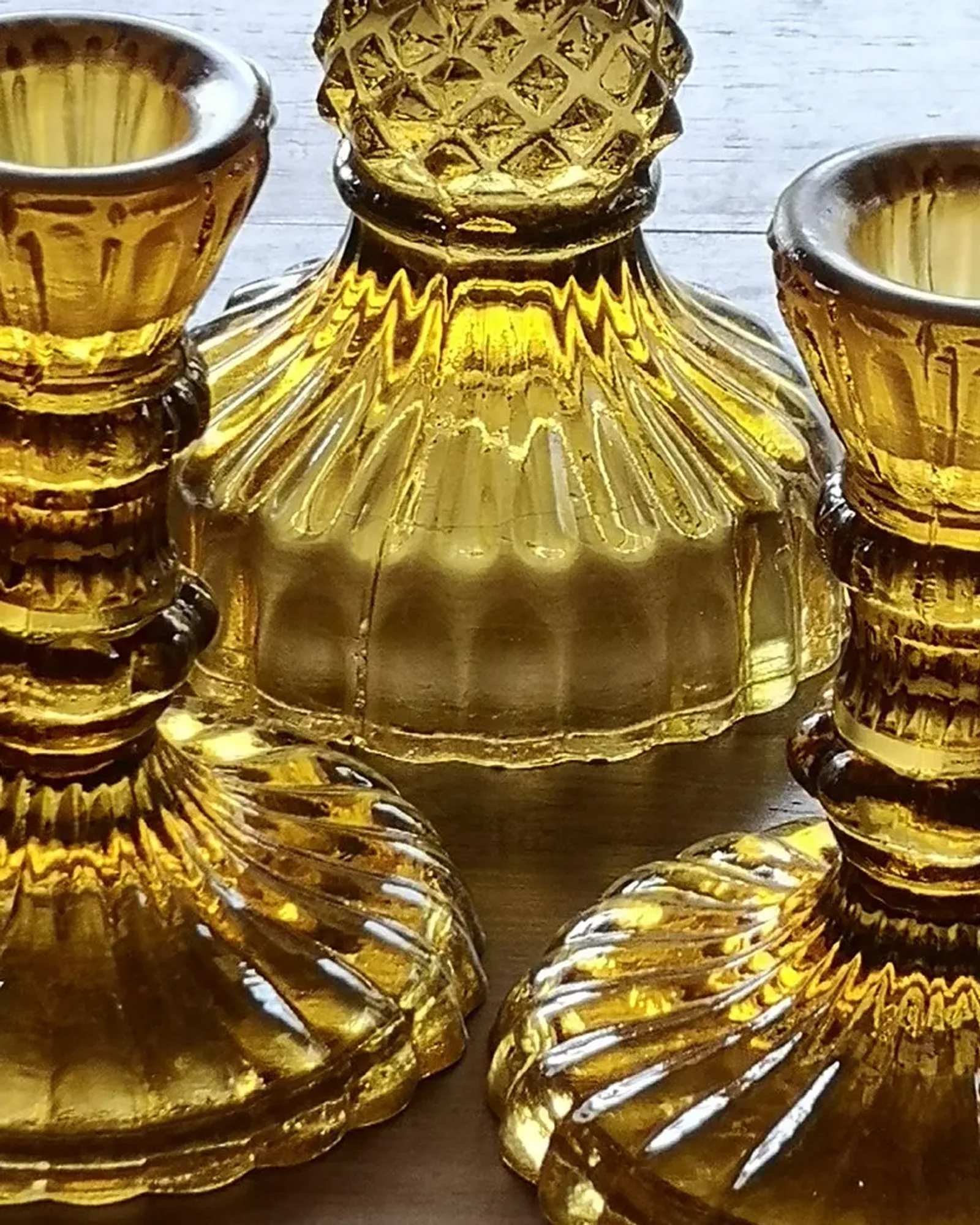 A short amber glass candlestick holding an unlit dinner candle, photographed on its own.