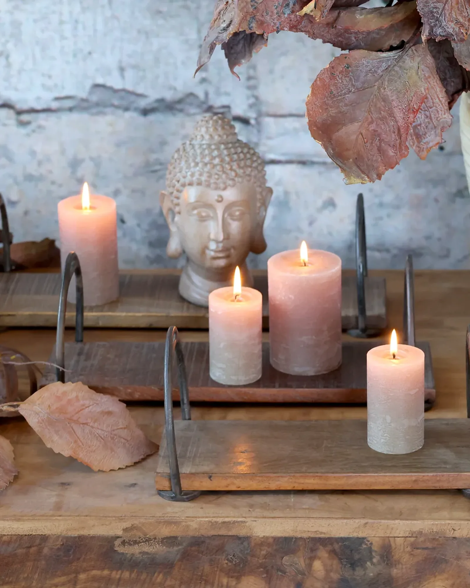Three nested natural-wood trays with arched iron end handles, set out with candles and foliage.