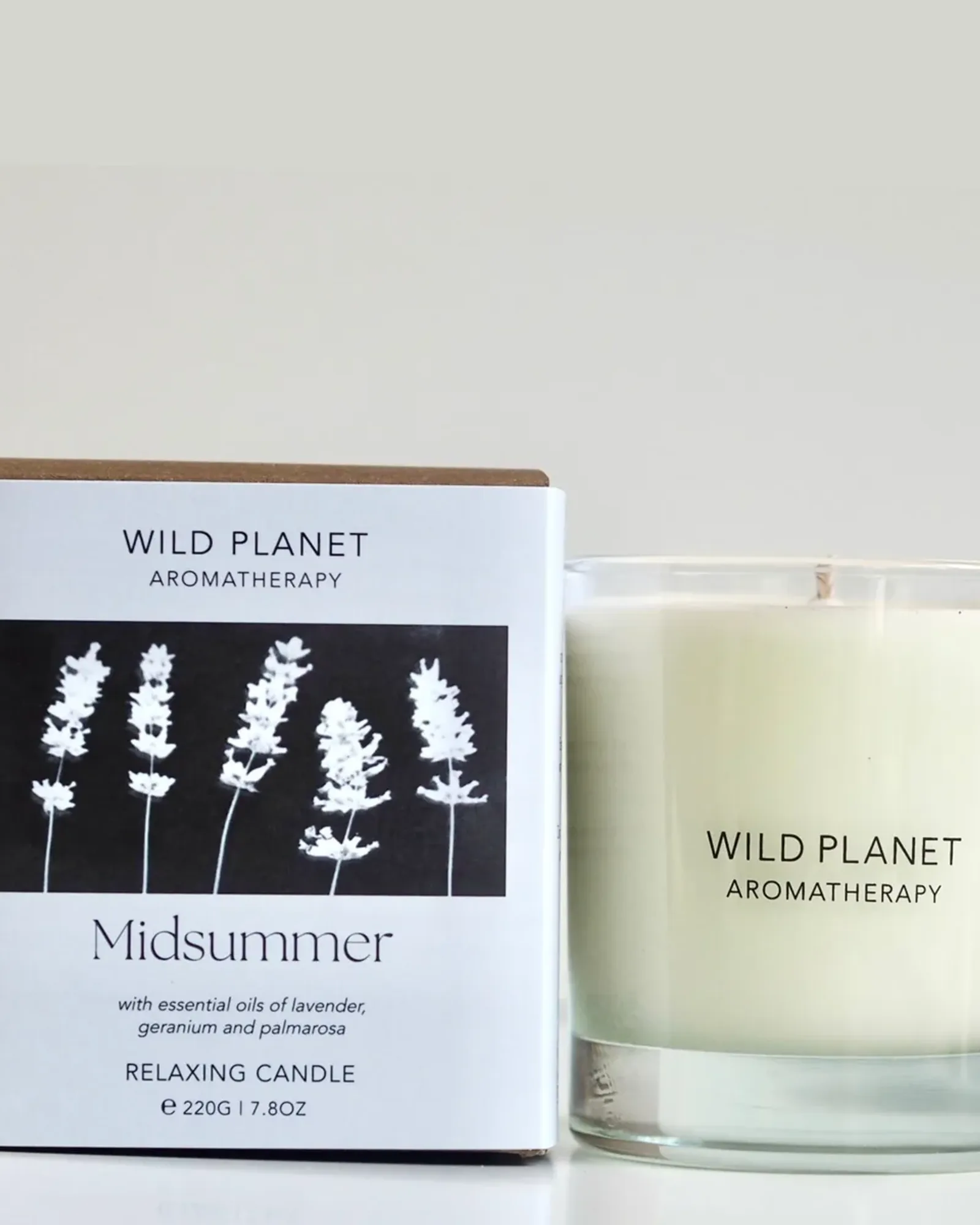 A Midsummer scented candle: soy wax with a single wick in a clear glass tumbler, beside its card box printed with the scent's name.