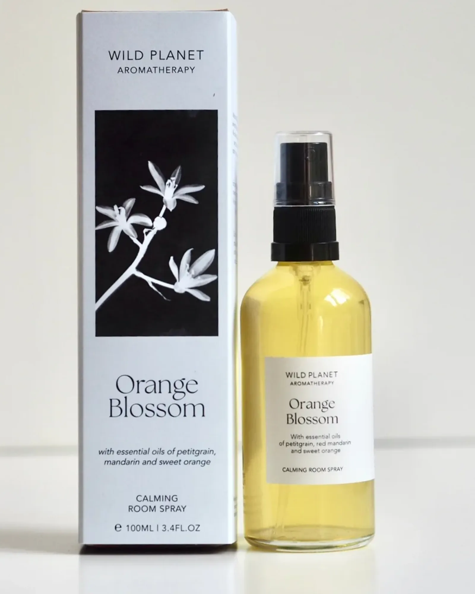 A clear glass bottle of Orange Blossom room spray with a black spray pump and a small cream label naming the scent.