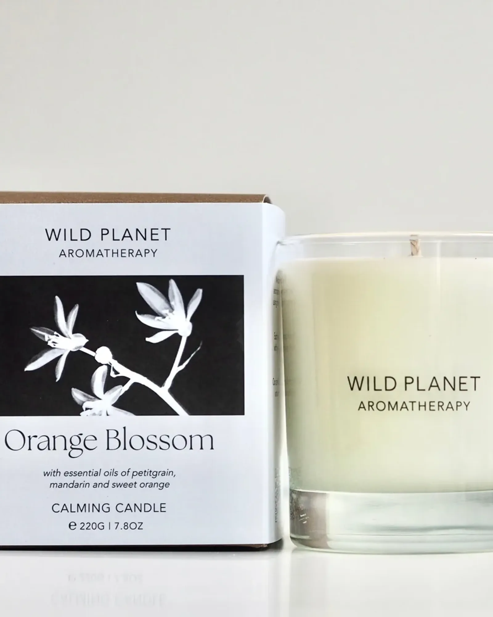 A Orange Blossom scented candle: soy wax with a single wick in a clear glass tumbler, beside its card box printed with the scent's name.