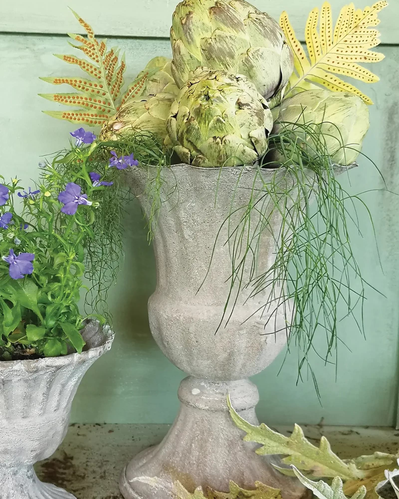 A grey vintage-style urn with an aged stone finish, photographed on its own against a plain background.