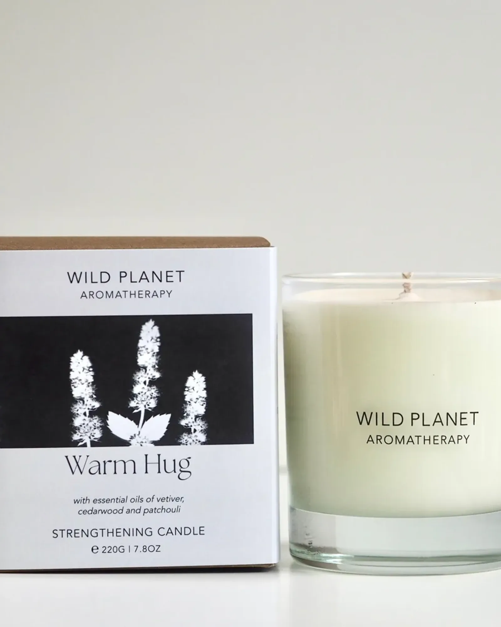 A Warm Hug scented candle: soy wax with a single wick in a clear glass tumbler, beside its card box printed with the scent's name.