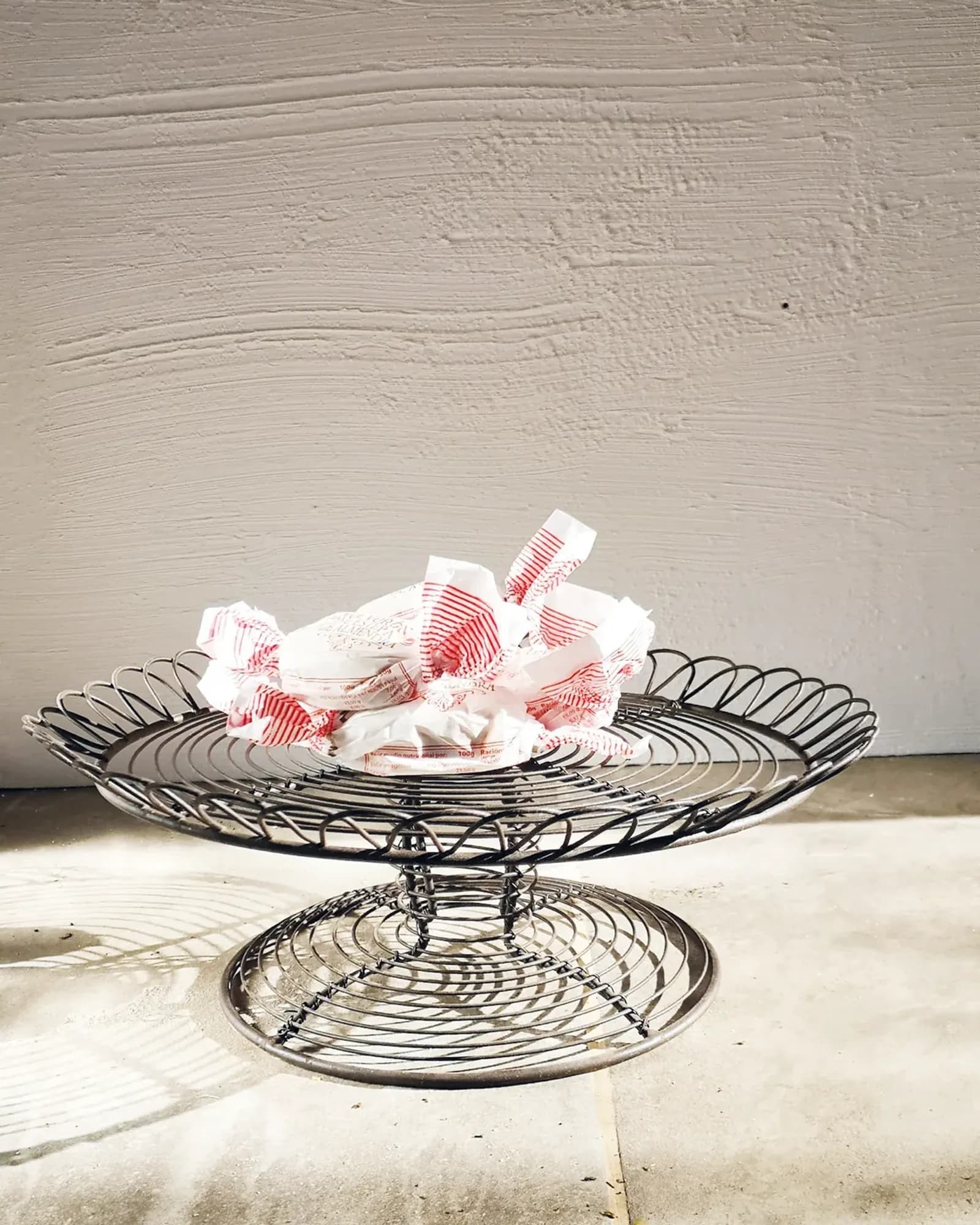 A round wire cake stand on a short foot in an antique rust finish, photographed on its own.