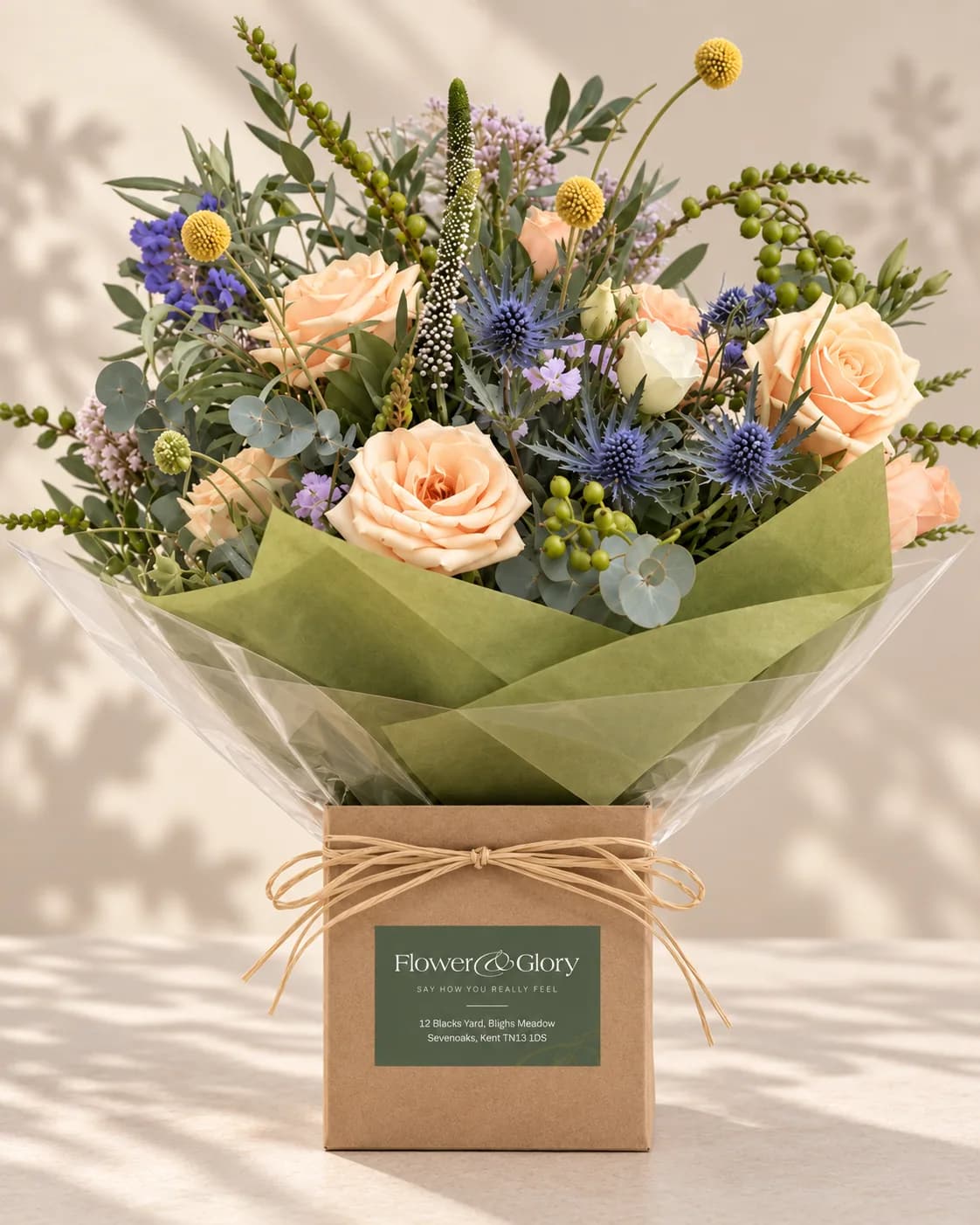 A seasonal hand-tied bouquet of roses, hydrangea and thistle, wrapped and ready for delivery